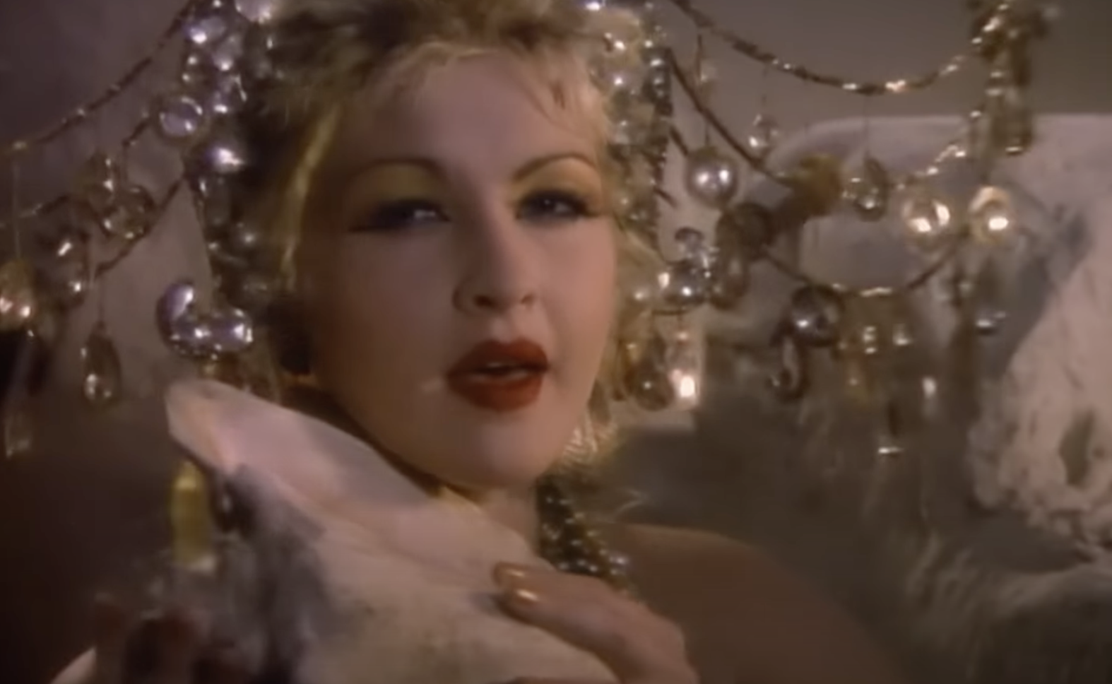Cyndi Lauper holding a seashell, wearing an elaborate headdress with dangling crystals