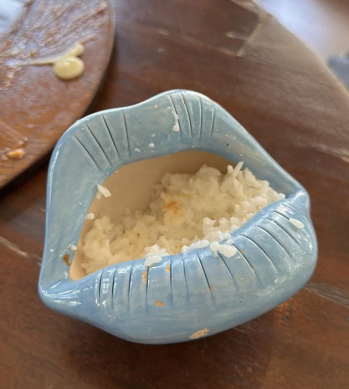 A ceramic bowl shaped like lips holds a serving of white rice.