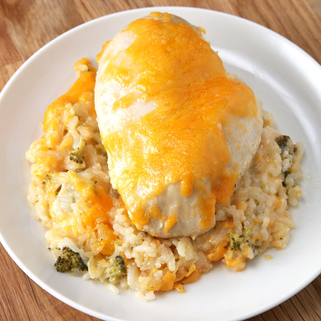 Chicken breast topped with melted cheese, served on a bed of creamy rice with broccoli on a white plate