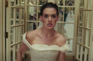 Anne Hathaway in "Bride Wars", wearing an off-shoulder bridal wedding dress, runs frantically indoors, appearing stressed