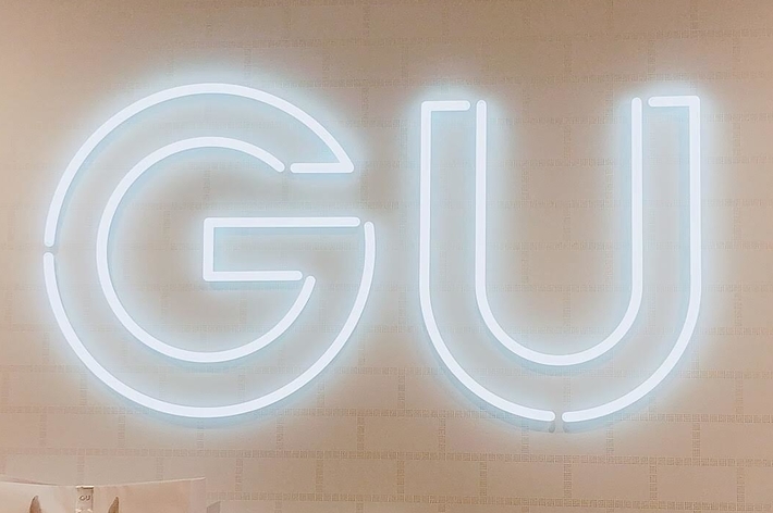 GU sign above several GU shopping bags in a retail setting