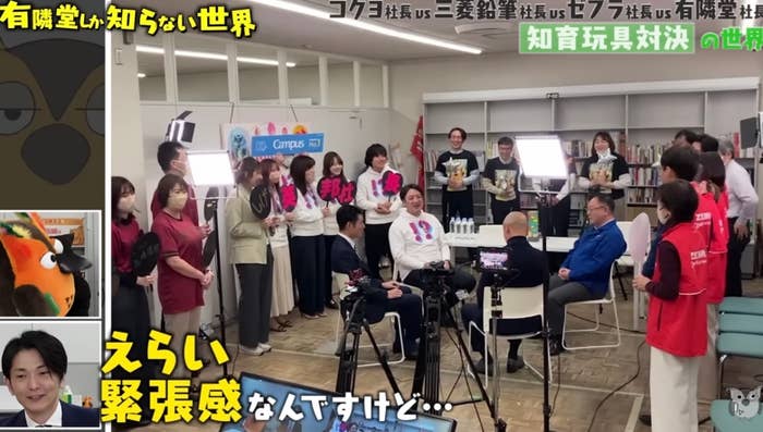 撮影現場にいる多くの人々がカメラに向かって微笑んでいます。