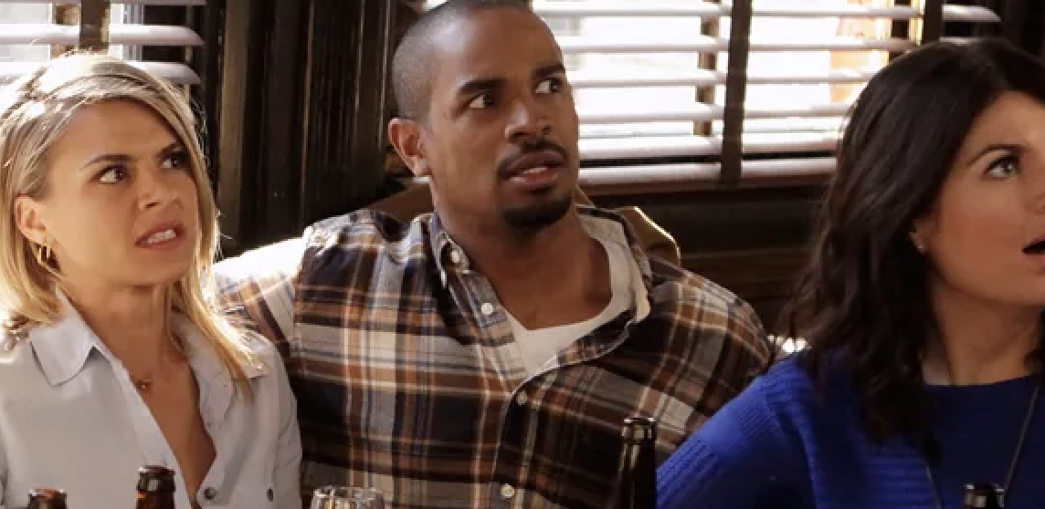 Eliza Coupe, Damon Wayans Jr., and Casey Wilson acting surprised while sitting at a table in a restaurant setting