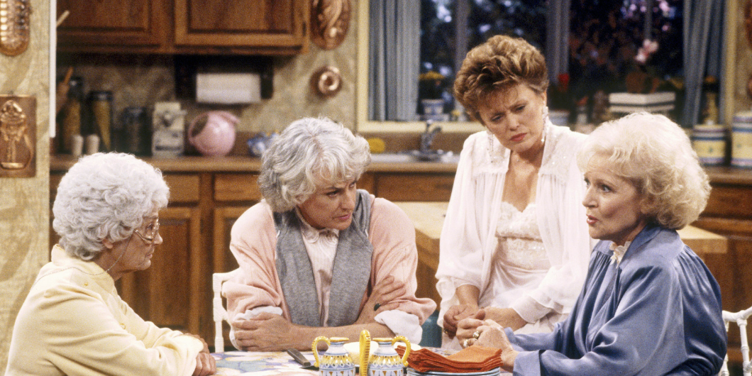 Estelle Getty, Bea Arthur, Rue McClanahan, and Betty White sit together in a kitchen, conversing at a table in a scene from &quot;The Golden Girls.&quot;