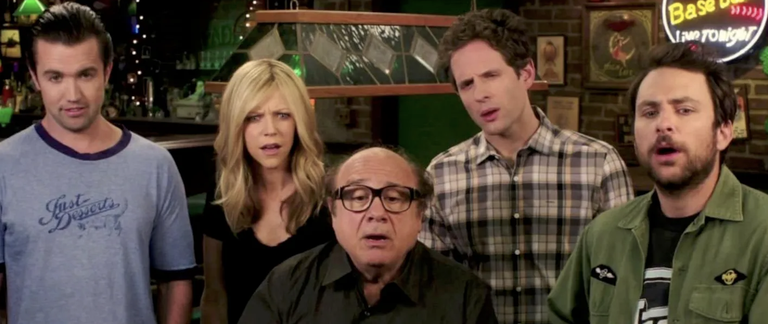 Charlie Day, Glenn Howerton, Rob McElhenney, Danny DeVito, and Kaitlin Olson in a bar, looking surprised or confused