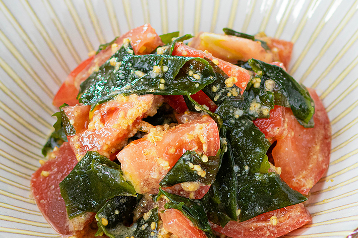 おいしそうなトマトとほうれん草の和え物が白いボウルに盛られている。