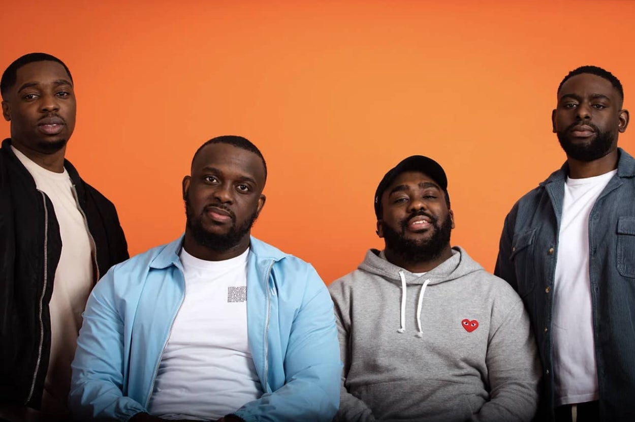 Four men, including Harry Pinero, Chuckie Online, Tazer Black, and Mr Exposed, pose together in casual outfits against an orange background