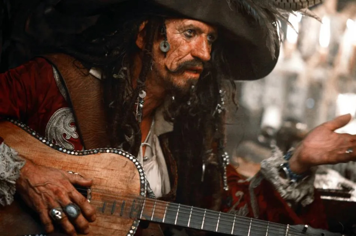 Johnny Depp dressed as Jack Sparrow from Pirates of the Caribbean, wearing a detailed pirate costume with a guitar
