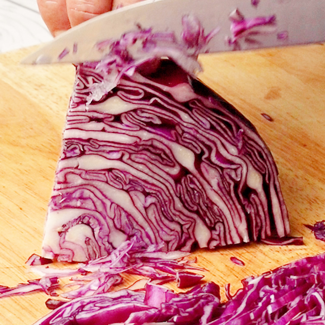 まな板の上でキャベツを包丁で切っている様子。