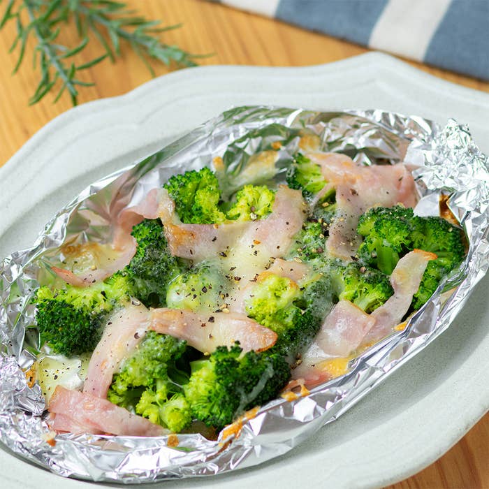 アルミホイルに包まれたブロッコリーとベーコンの料理が皿に盛られています。