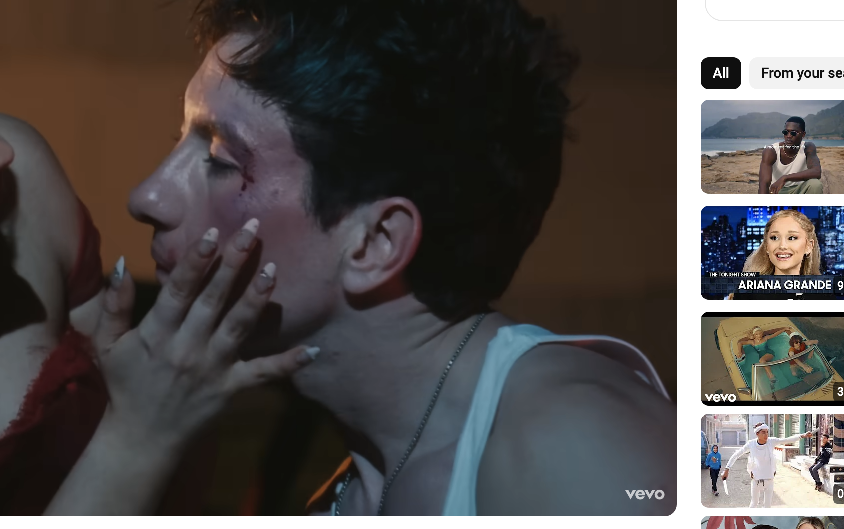 Screenshot from Sabrina Carpenter&#x27;s official music video for &quot;Please Please Please,&quot; showing a dramatic scene of a blood-streaked man in a white tank top being touched by a woman