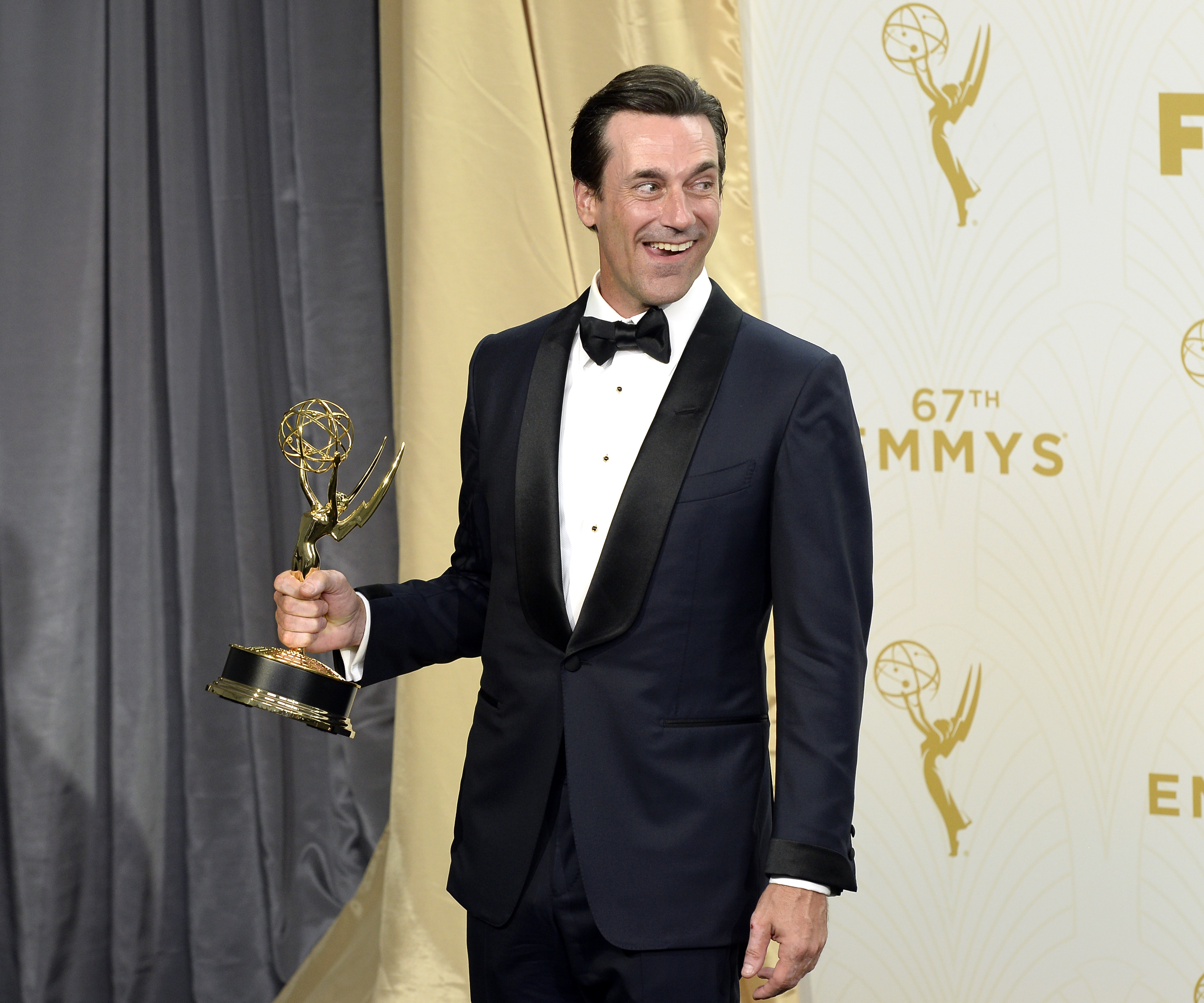 Jon Hamm in a tuxedo holding an Emmy award at the 67th Primetime Emmy Awards