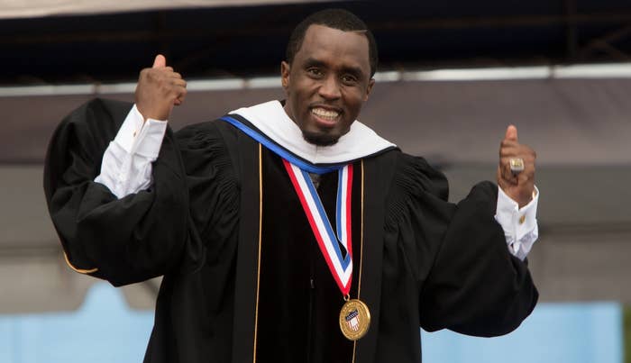 Sean &quot;Diddy&quot; Combs smiles and raises both fists in celebration while wearing academic regalia and a medal