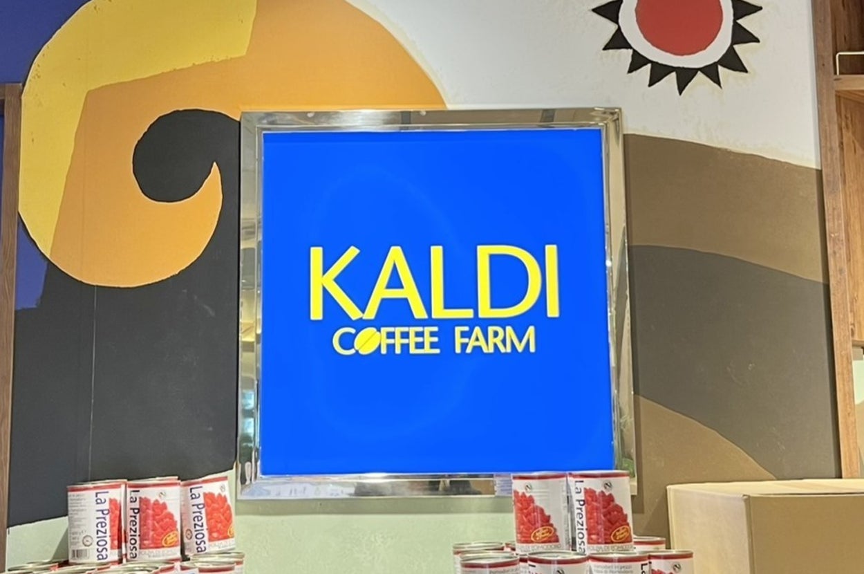 カルディコーヒーファームの看板とトマト缶が並んだディスプレイが写っている。