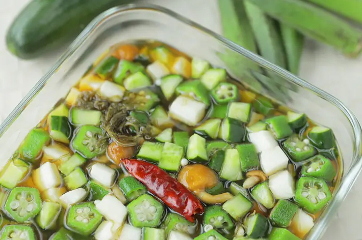 ガラスの容器に盛られた刻んだオクラと他の野菜が入った料理の画像。隣にはキュウリと他の野菜が置かれています。