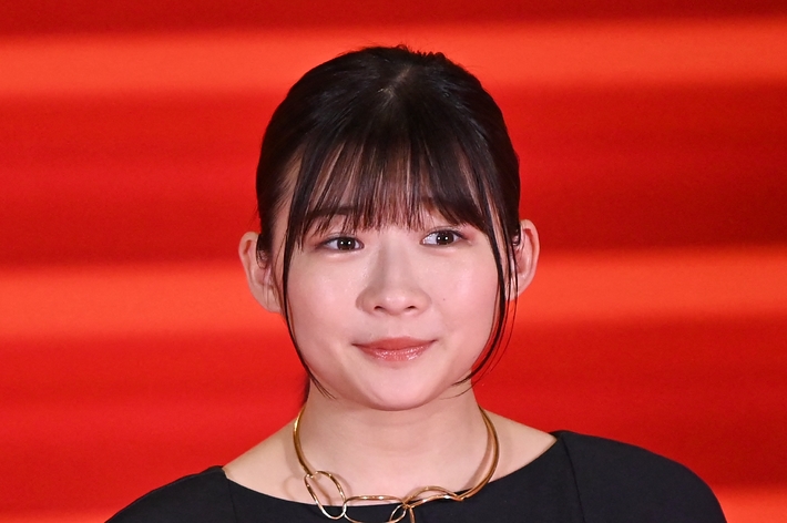 女性が赤いカーペット上で黒いドレスを着ています。