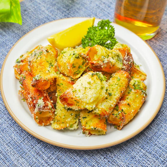 白い皿に盛り付けられたパセリとパルメザンチーズがかかったポテト料理、横にはレモンのスライスとパセリが添えられています。