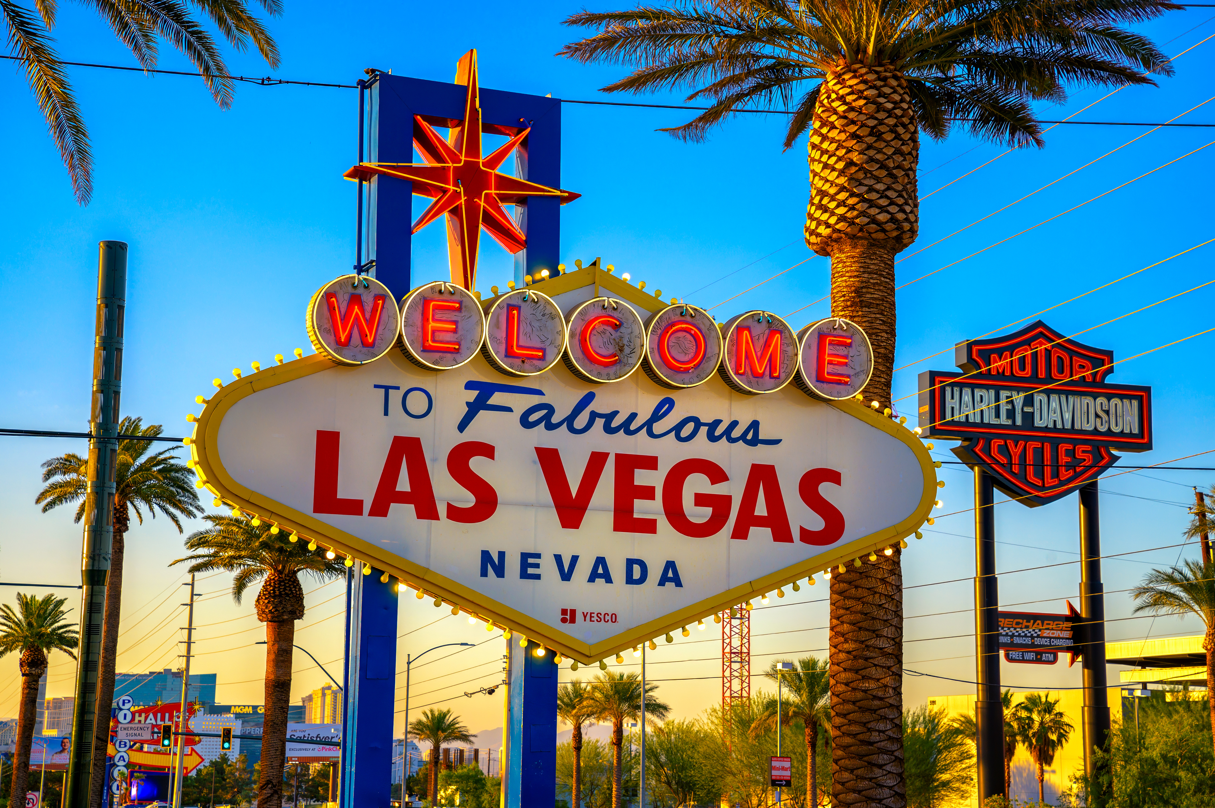 "Welcome to Fabulous Las Vegas Nevada" sign with palm trees and Harley-Davidson sign in the background