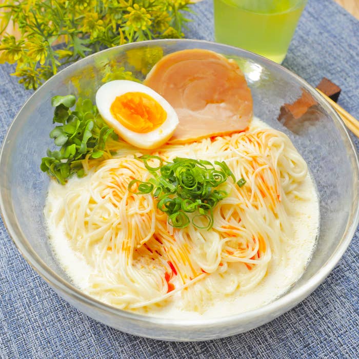 ラー油と刻みネギ、半熟卵、チャーシューをトッピングしたそうめんが皿に盛られている。