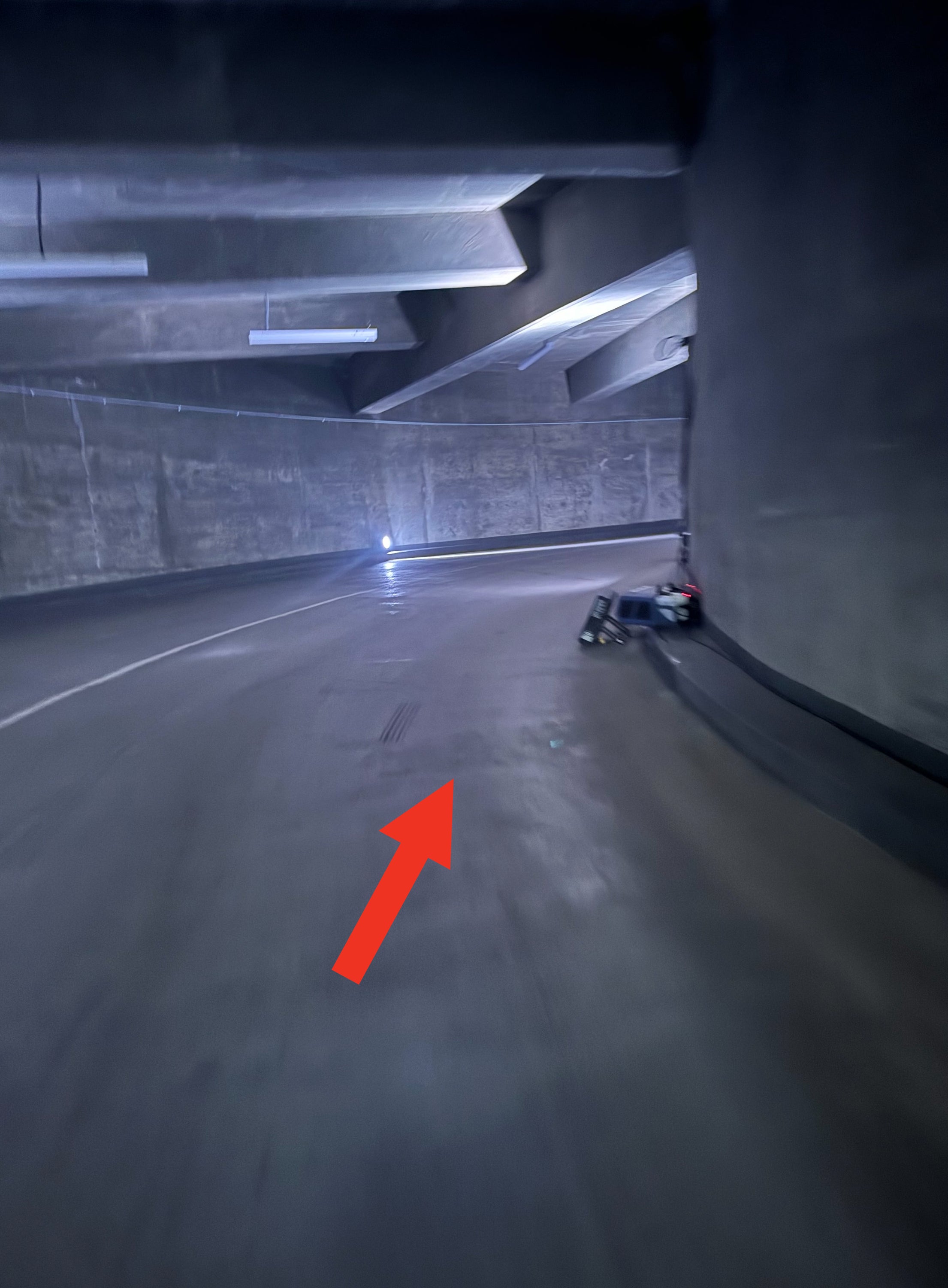 A blurry, empty, curved parking garage with overhead lights. There's a distant, unclear light source