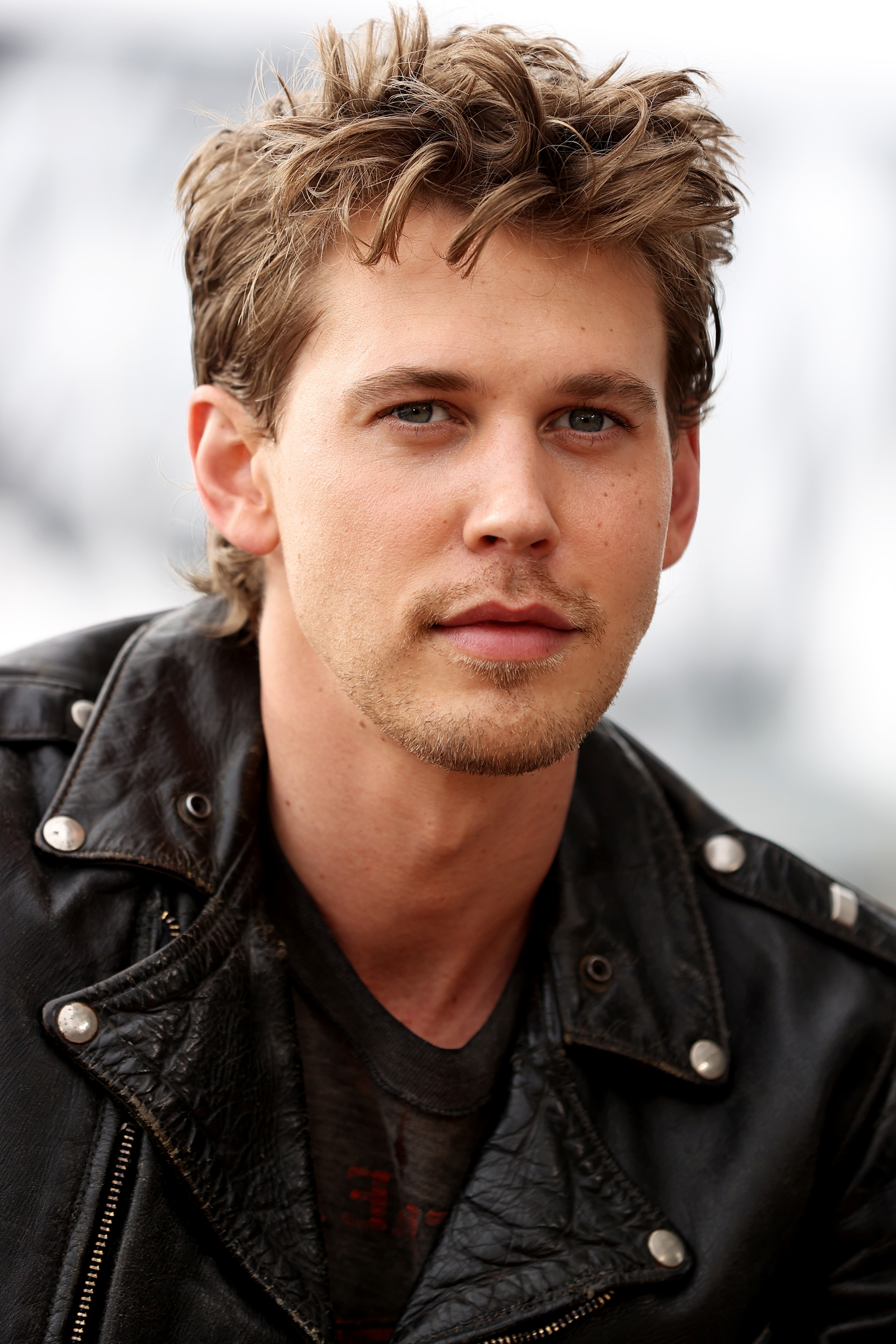 Austin Butler in a leather jacket, looking at the camera with a neutral expression
