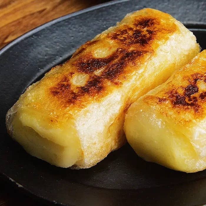 黒い皿に盛られた二つの焼き餃子。焦げ目が付いて美味しそうに見える。