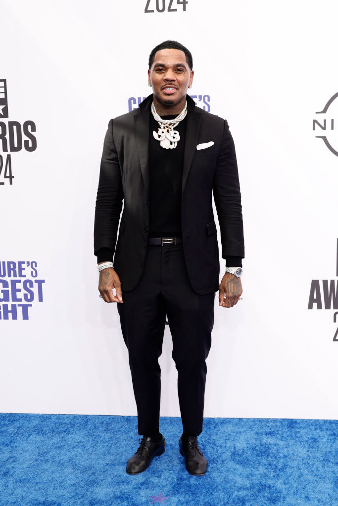 Kevin Gates on the red carpet, wearing a black suit with a black turtleneck, accessorized with a silver pendant necklace, at the Culture's Biggest Night Awards 2024