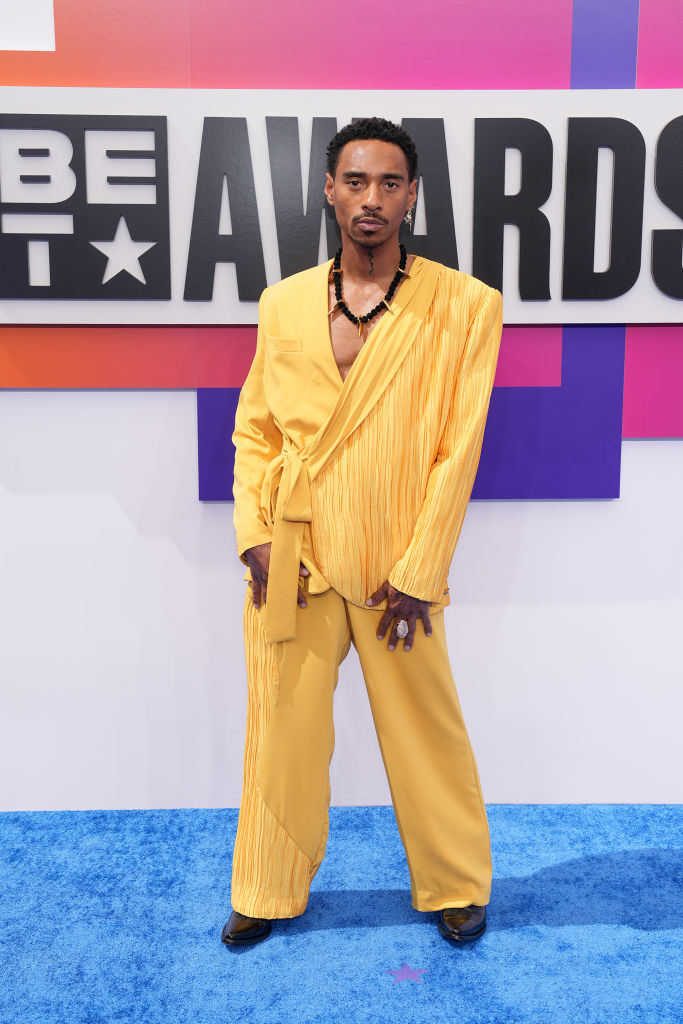 Durand Bernarr in a fashionable, asymmetrical yellow suit stands on the red carpet at the BET Awards