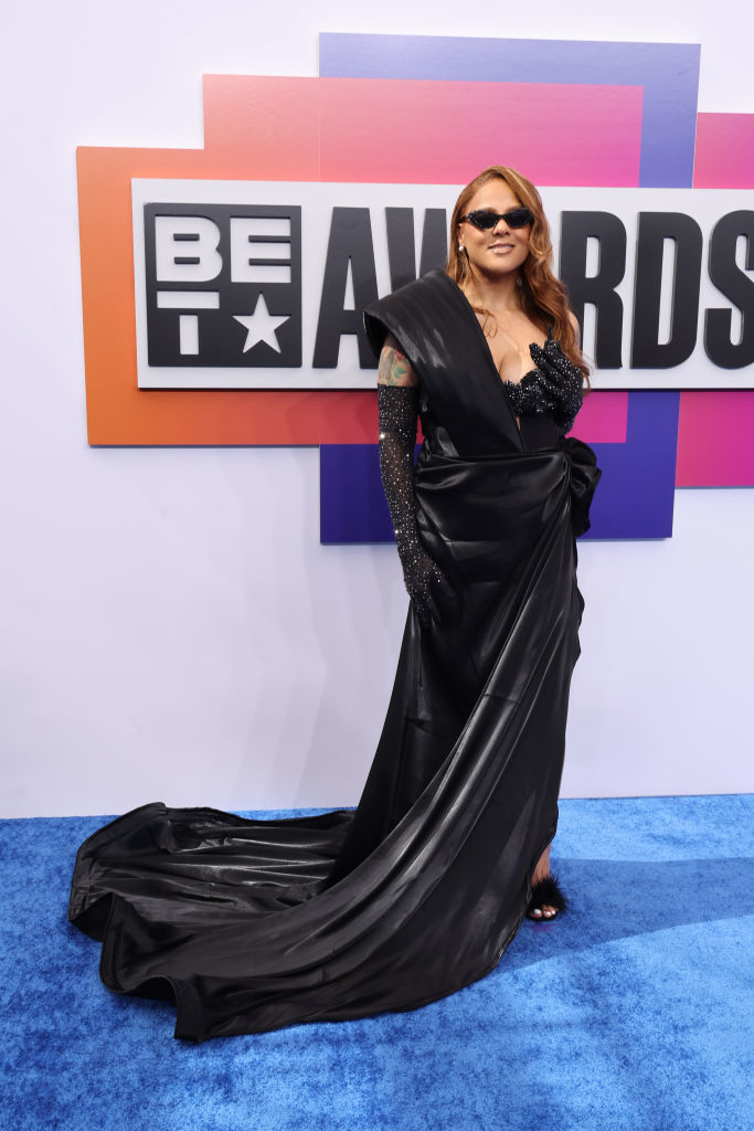 Marsha Ambrosius wears a black gown with glittery long sleeves on the red carpet at the BET Awards, standing in front of a large event sign