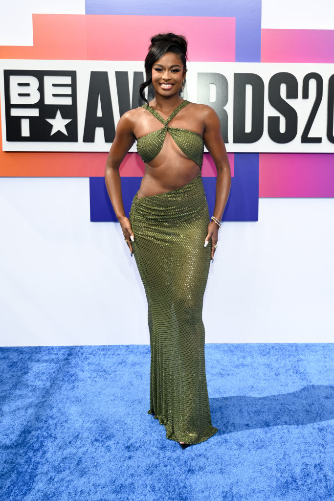 Coco Jones in a shimmering, cut-out green gown at the BET Awards red carpet, smiling and posing for photos