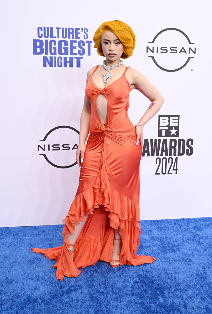 Ice Spice stands on the red carpet at the 2024 BET Awards in an elegant cut-out gown with a dramatic train and ornate necklace
