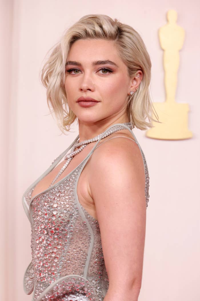 Florence Pugh posing on the red carpet in a bejeweled dress with a plunging neckline at an awards event