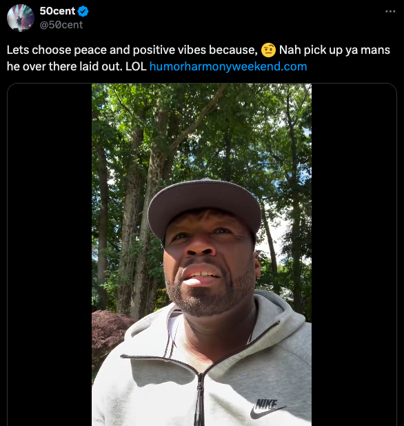 50 Cent in a grey Nike hoodie and cap, outdoors with trees in the background. Top text: &quot;Lets choose peace and positive vibes...&quot; Bottom text: &quot;humorharmonyweekend.com.&quot;