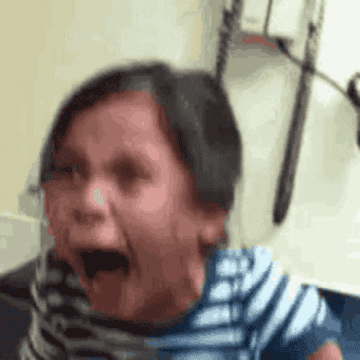 Niño pequeño llorando fuertemente con una expresión de angustia. Lleva una camiseta de rayas