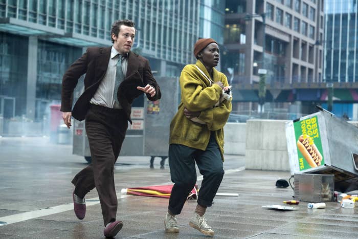 Joseph Quinn, Lupita Nyong'o, and Frodo running in an urban setting in a scene from &quot;A Quiet Place: Day One&quot;