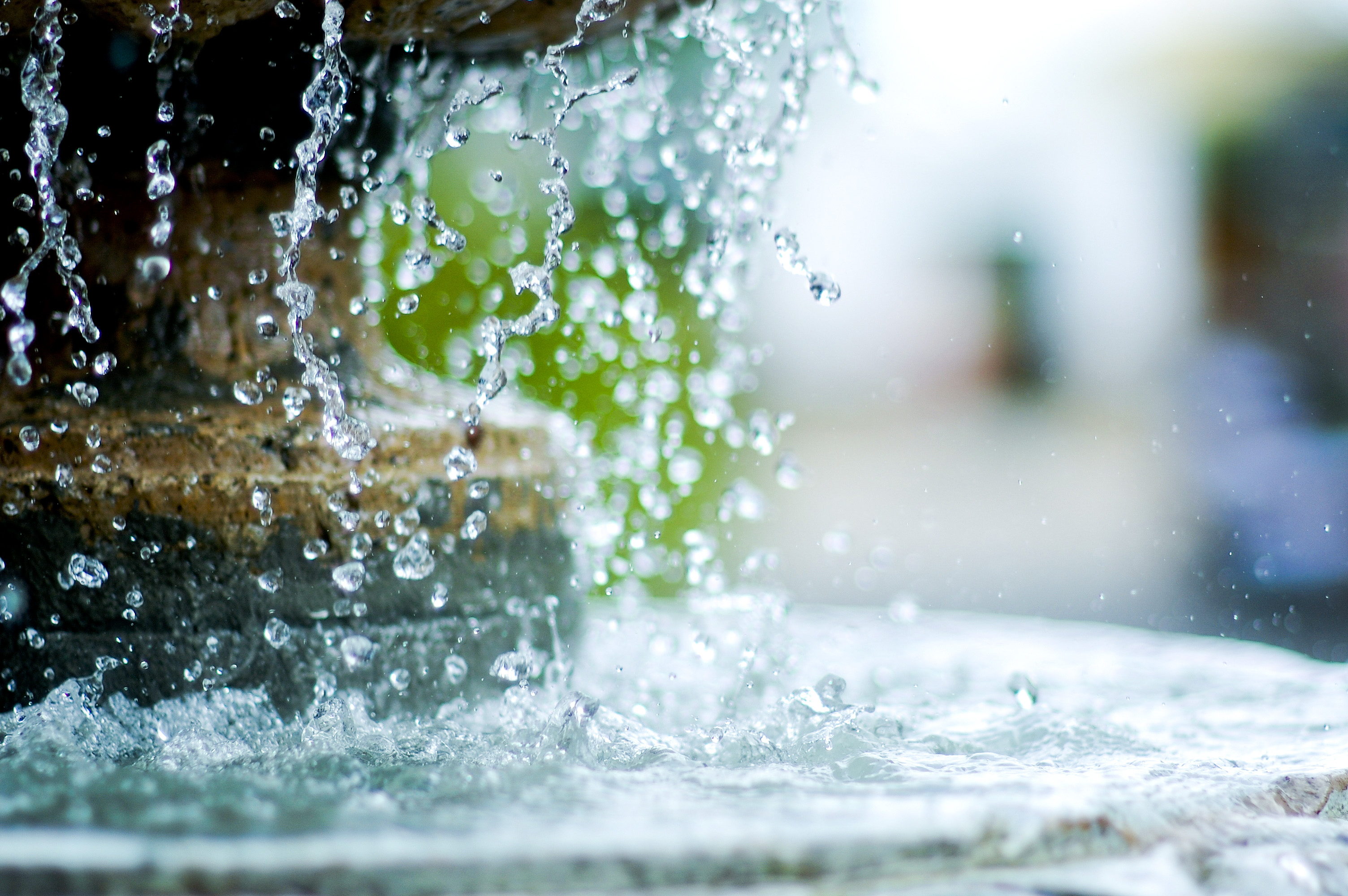 Close-up of a fountain with water droplets splashing over the edge, creating a dynamic and refreshing scene