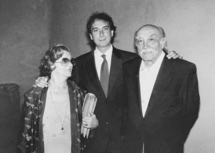 In this black-and-white photo, three people pose together: an elderly woman in sunglasses, a middle-aged man in a suit, and an elderly man in a suit