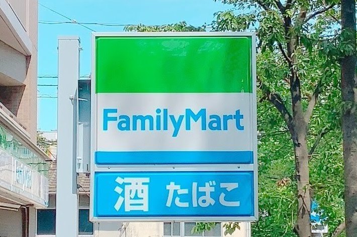ファミリーマートの看板。「酒」「たばこ」の表示あり。背景に店舗と自然環境が見える。