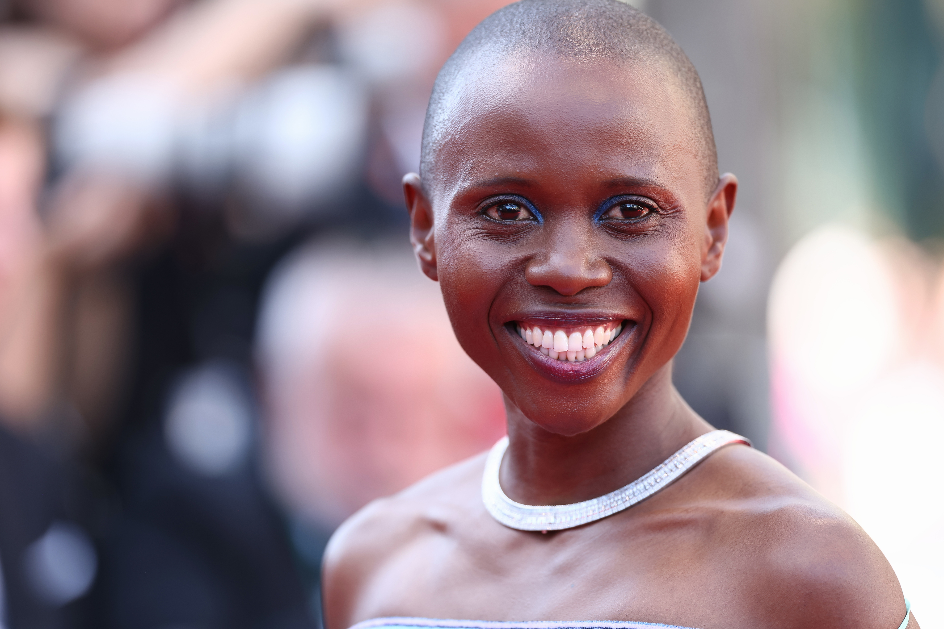 Eliane Umuhire smiling on the red carpet, wearing a sleeveless dress