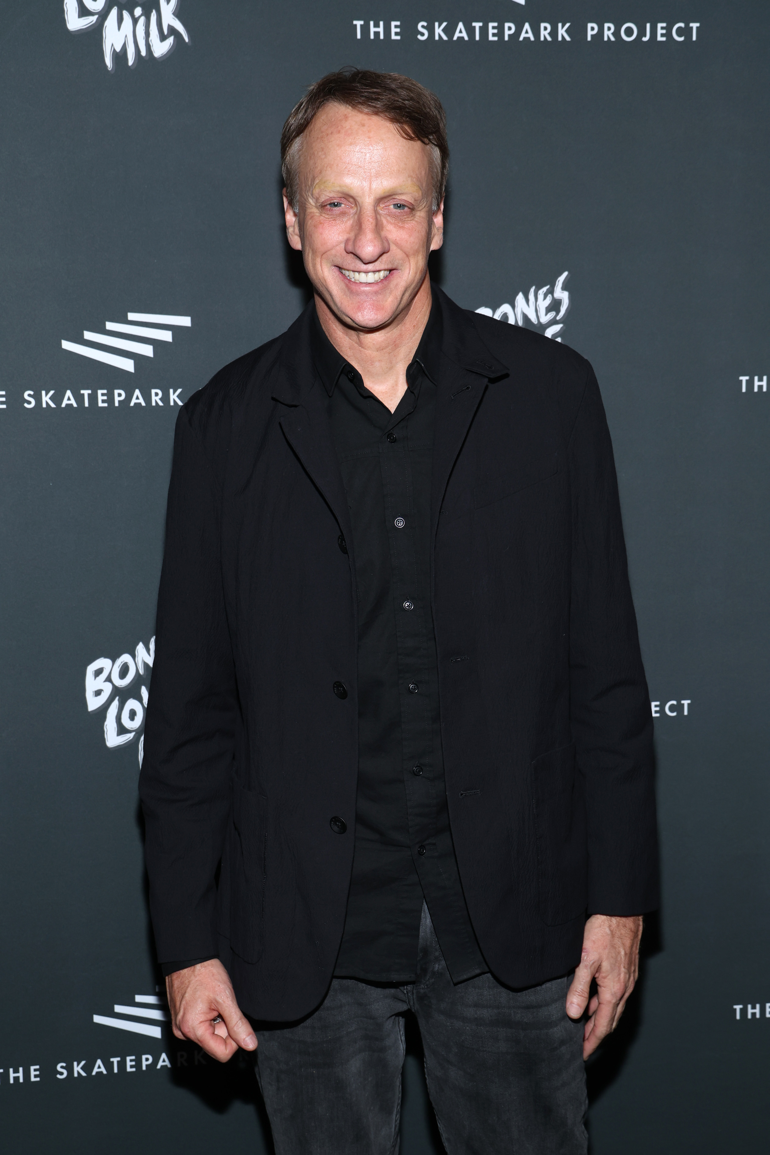 Tony Hawk at The Skatepark Project event, wearing a black jacket and shirt