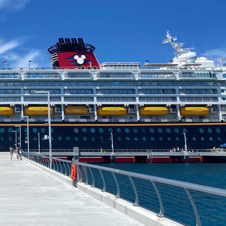A large Disney cruise ship docked at a pier on a clear day