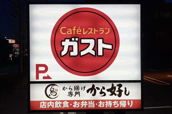 ガストの広告看板。カフェレストランガストと記載。下部には「からあげ専 門」、店内飲食、お弁当、お持ち帰り」とあります。