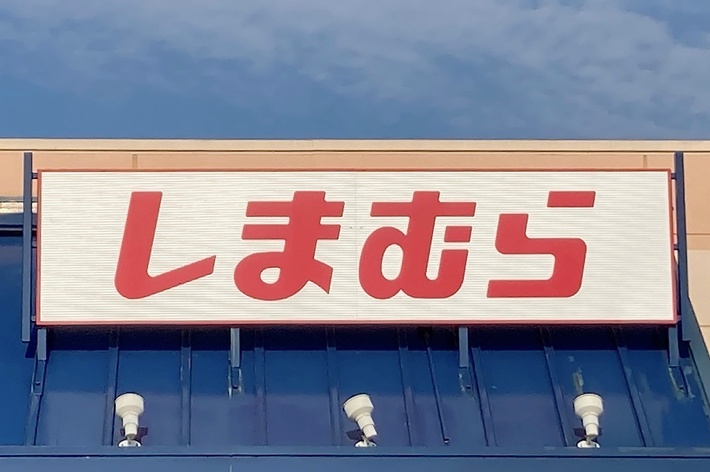 Storefront with a sign in Japanese characters &ldquo;しまむら&rdquo; under a blue sky