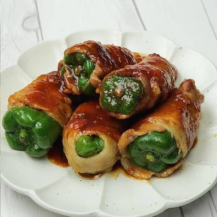 皿の上に盛られた4つのピーマンの肉詰め。ソースがかかっています。