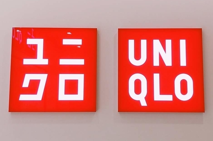 Two red signs with white text: The left sign has Japanese characters, and the right sign reads &ldquo;Uniqlo.&quot;