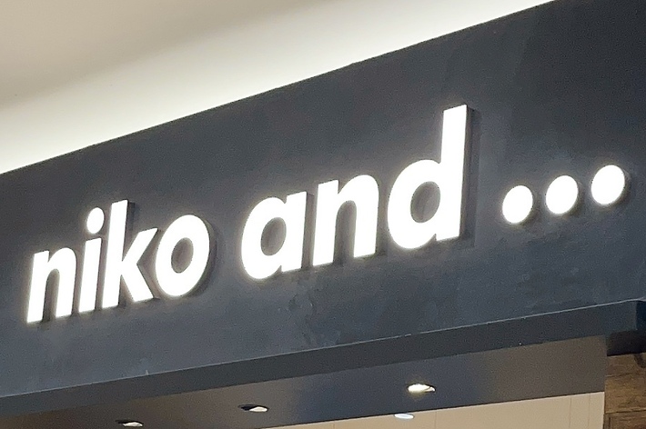 Storefront of &ldquo;niko and &hellip;&rdquo; showing various clothing and home goods, with a sign inside promoting LUSH fresh handmade cosmetics