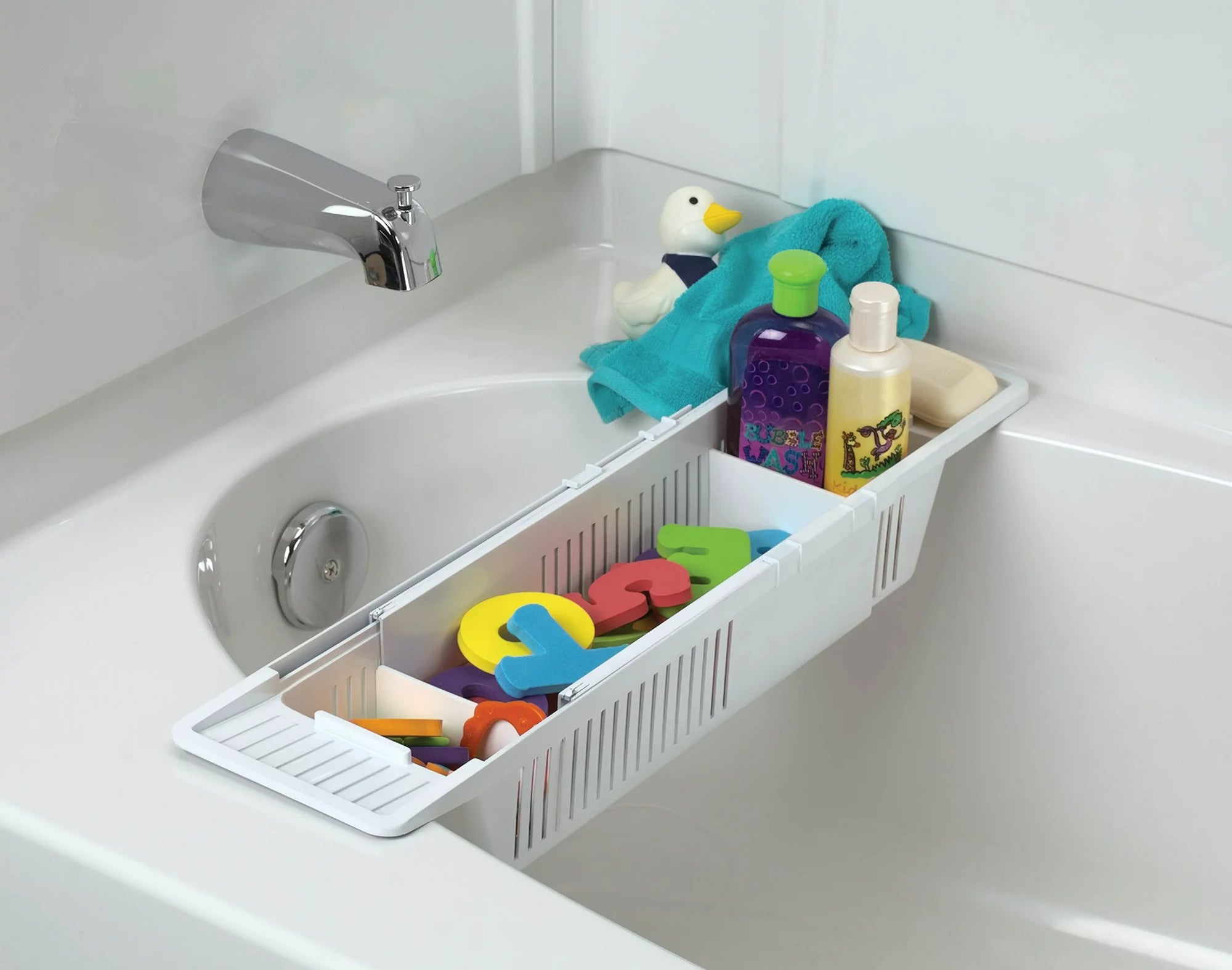 Caddy mandi dengan mainan mandi, dua botol produk mandi, dan waslap ditempatkan di atas faucet di bak mandi putih