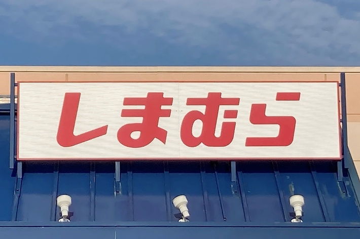 Storefront with Japanese sign reading &ldquo;Shimamura,&rdquo; under a blue sky. Handicap parking sign is visible
