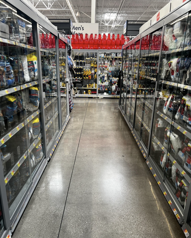 Store aisle with men's grooming products on both sides. Multiple shelves display various items like razors, shaving creams, and grooming kits