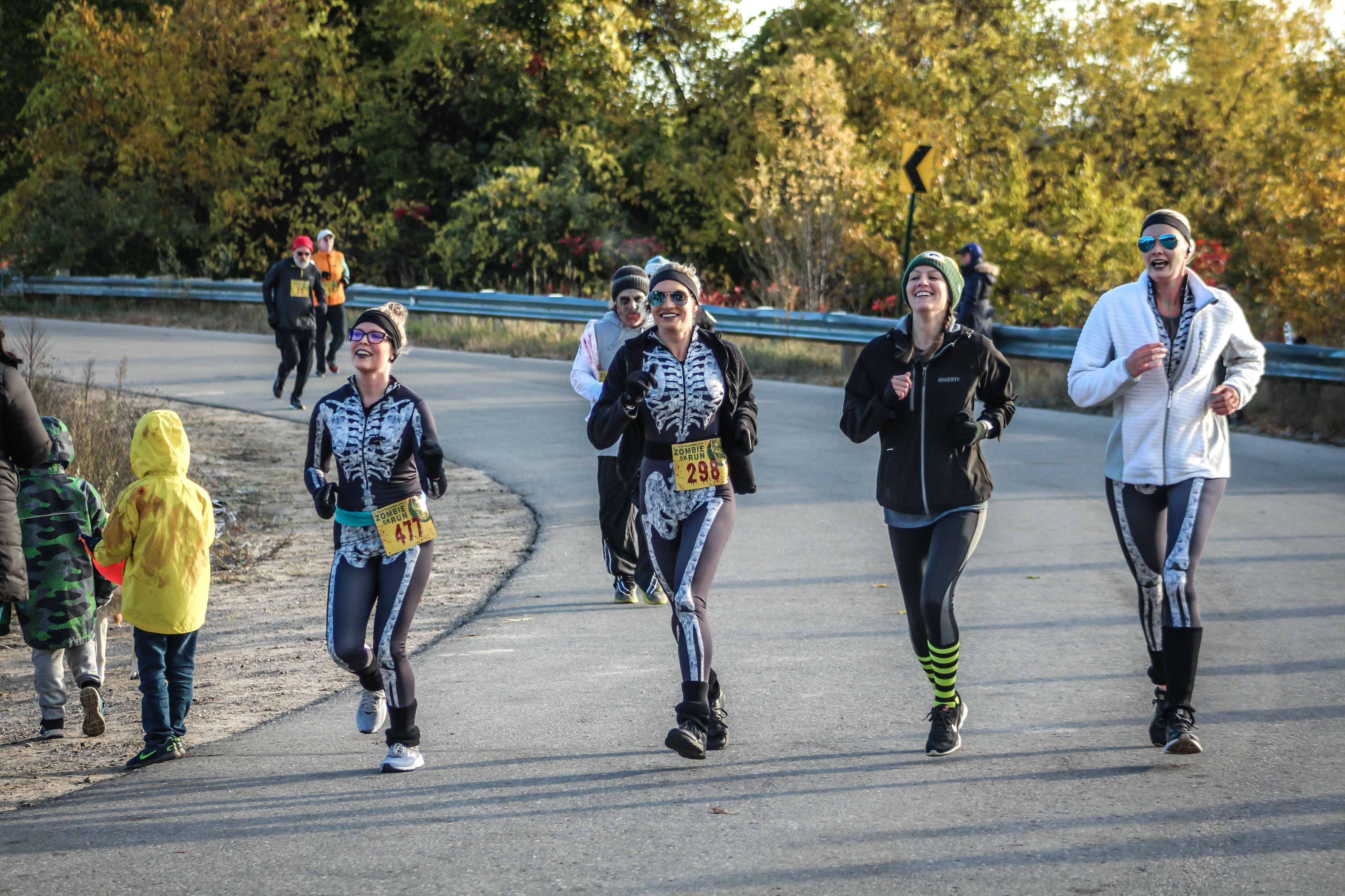 People in skeleton-themed athletic outfits running on a road during a race